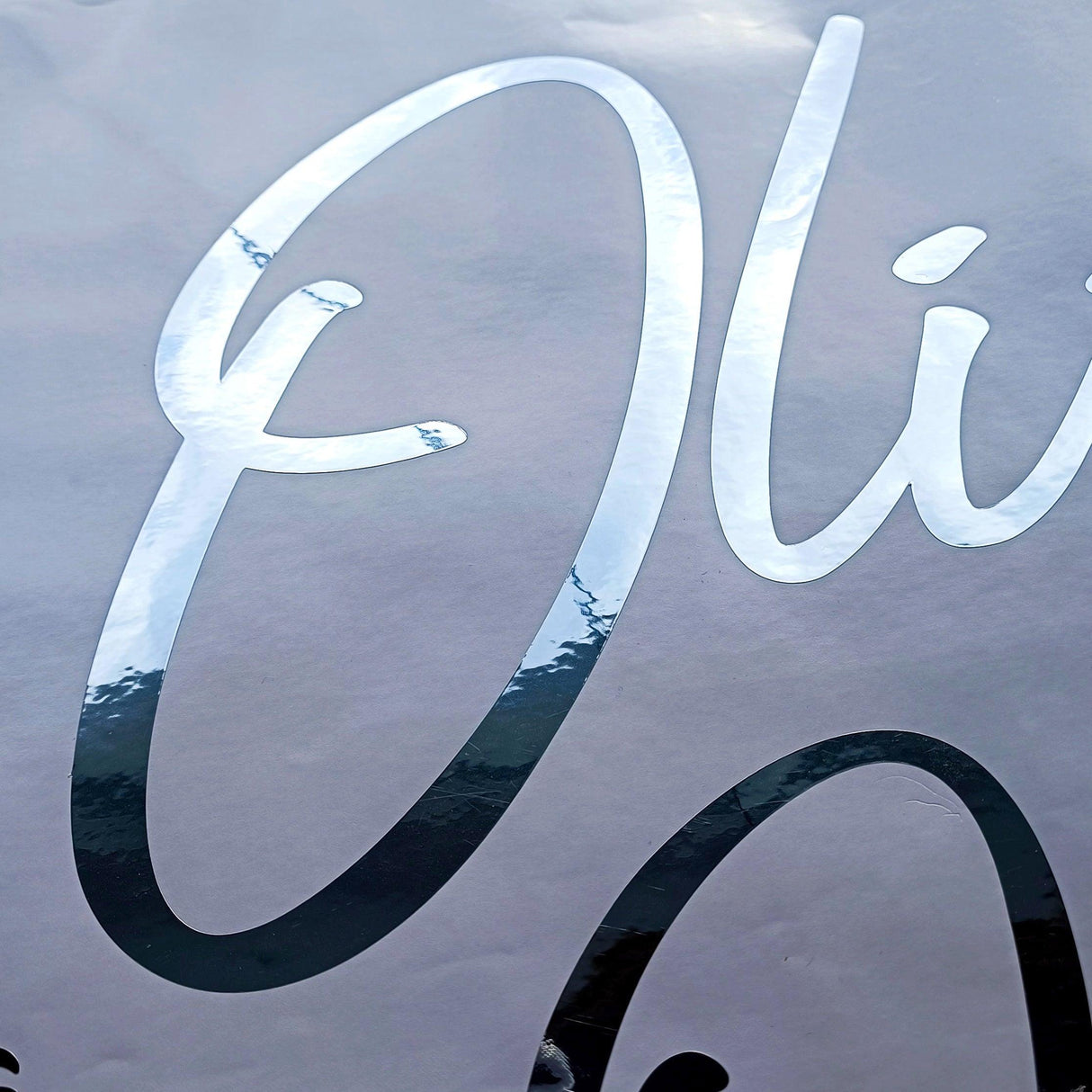 Personalized vinyl name sticker in silver chrome finish featuring the name 'Olivia' for stylish labeling.