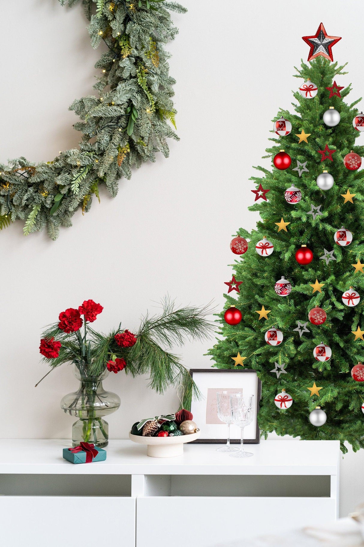 Colorful Christmas tree wall vinyl decal with ornaments next to holiday wreath and floral arrangement.