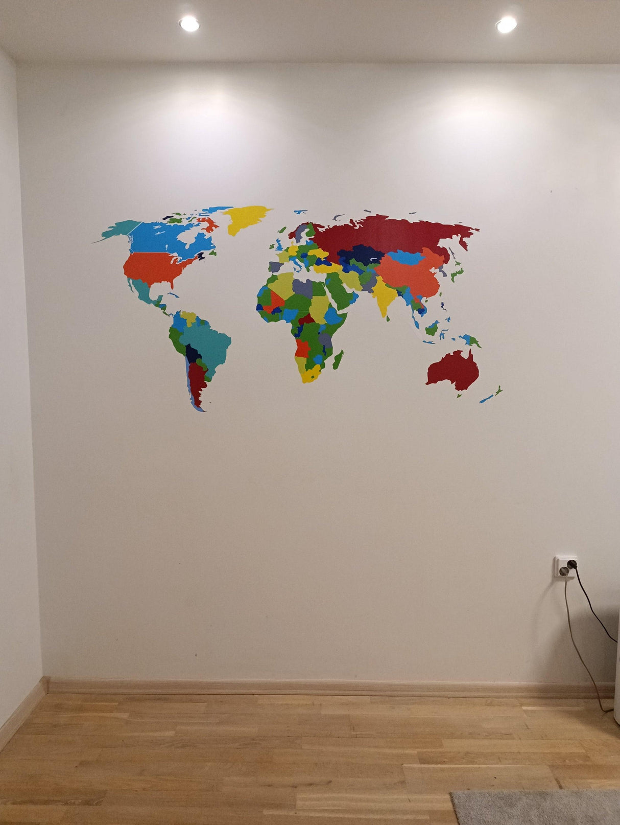 Colorful world map wall sticker on a white wall, perfect for home decor and travel enthusiasts.