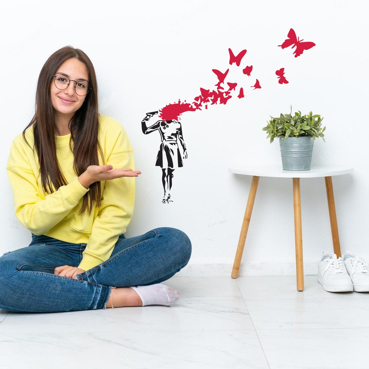 Banksy Suicide Girl With Butterfly wall decal displayed beside a smiling woman in casual attire, enhancing modern decor.