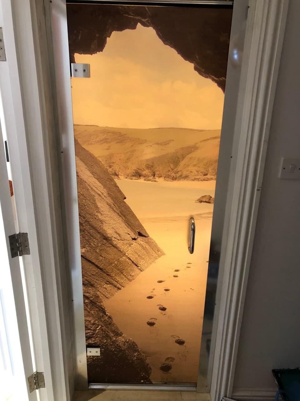 Scenic beach vista door decal featuring sandy footprints and rocky cliffs, perfect for home decor.