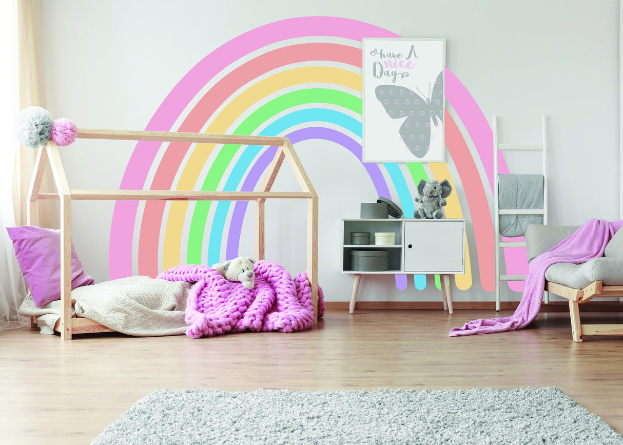Pastel rainbow wall sticker in a cozy nursery with soft furnishings and boho decor.