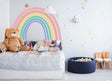 Pastel rainbow wall sticker in a cute bedroom with stuffed animals, adding color and cheer to the space.
