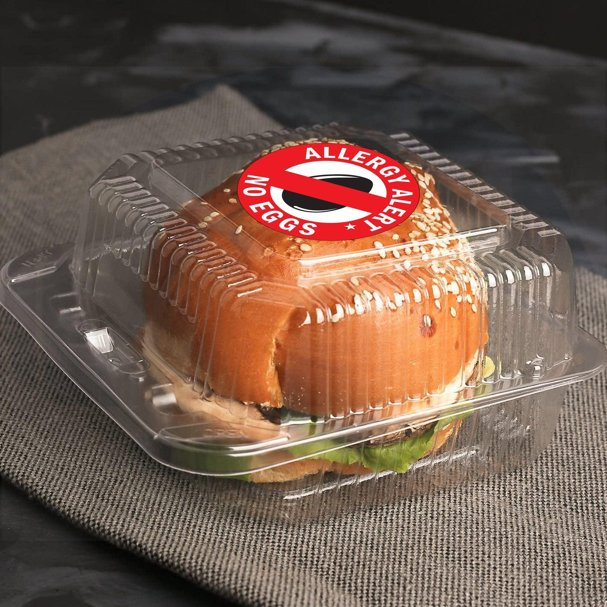 Sandwich in a clear container with a round sticker saying 'Allergy Alert: No Eggs' for allergy awareness.
