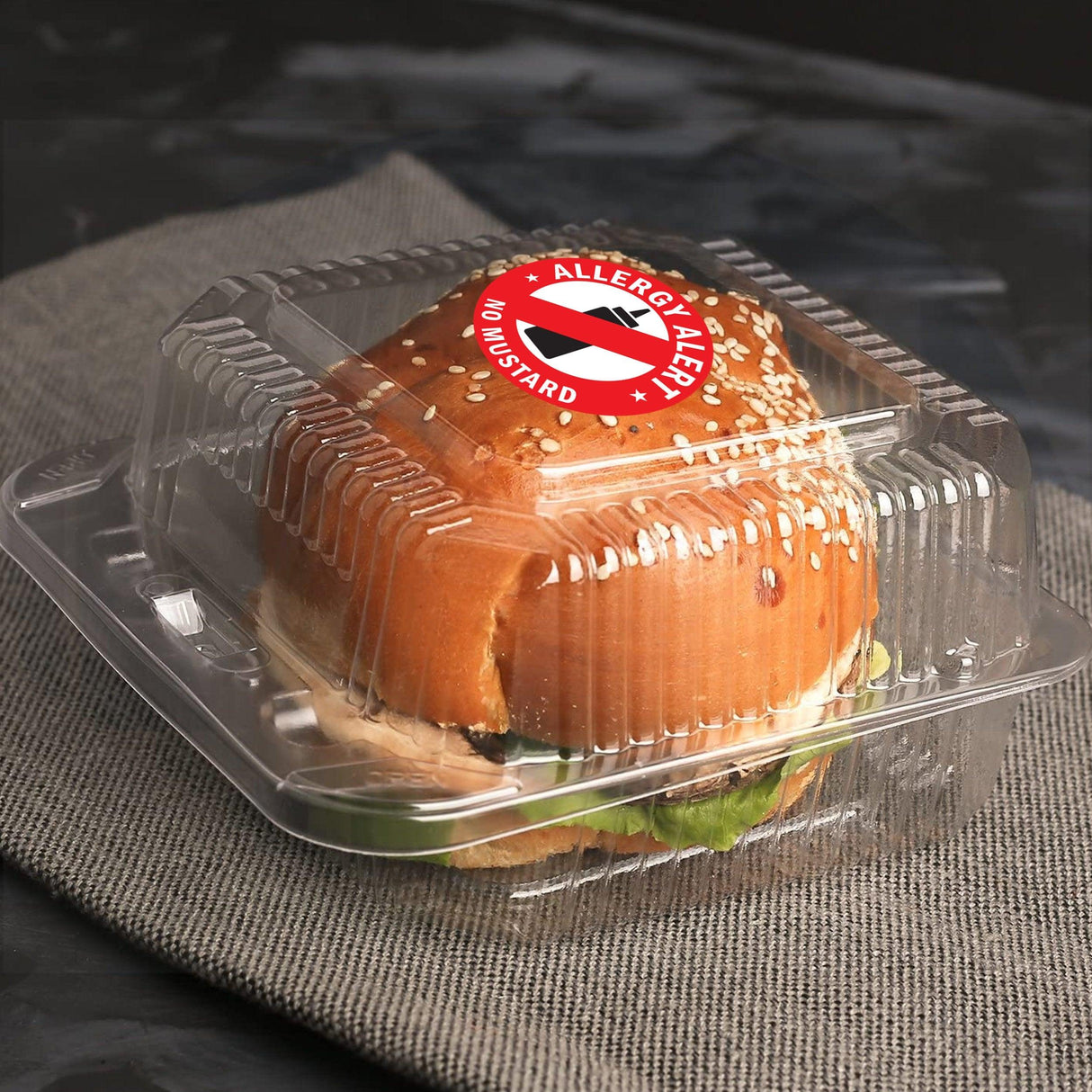 Clear container holding a sandwich with a No Mustard Allergy Alert Sticker on top, promoting food allergy awareness.