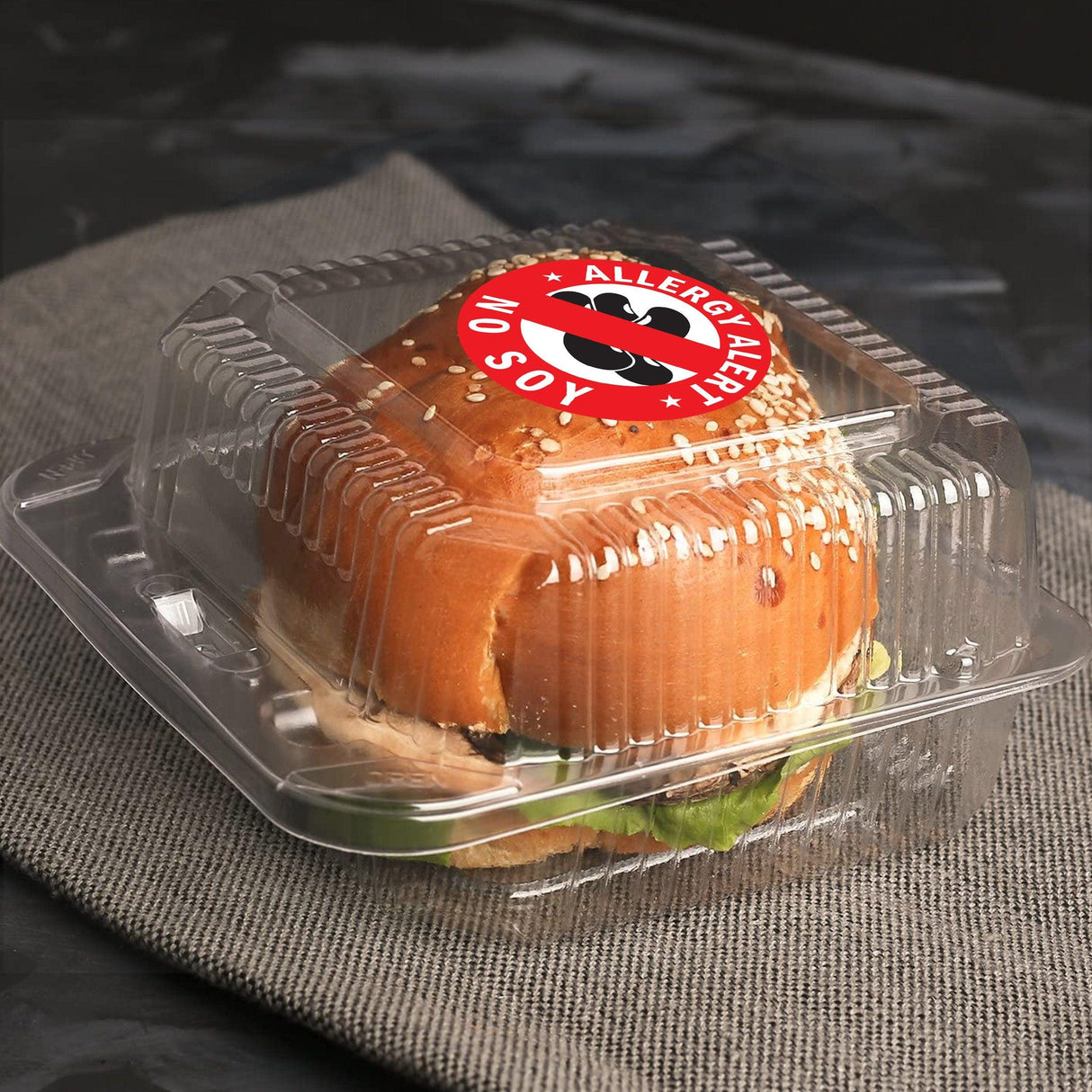 Burger in a clear container with a No Soy Allergy Alert sticker on top for safety awareness.