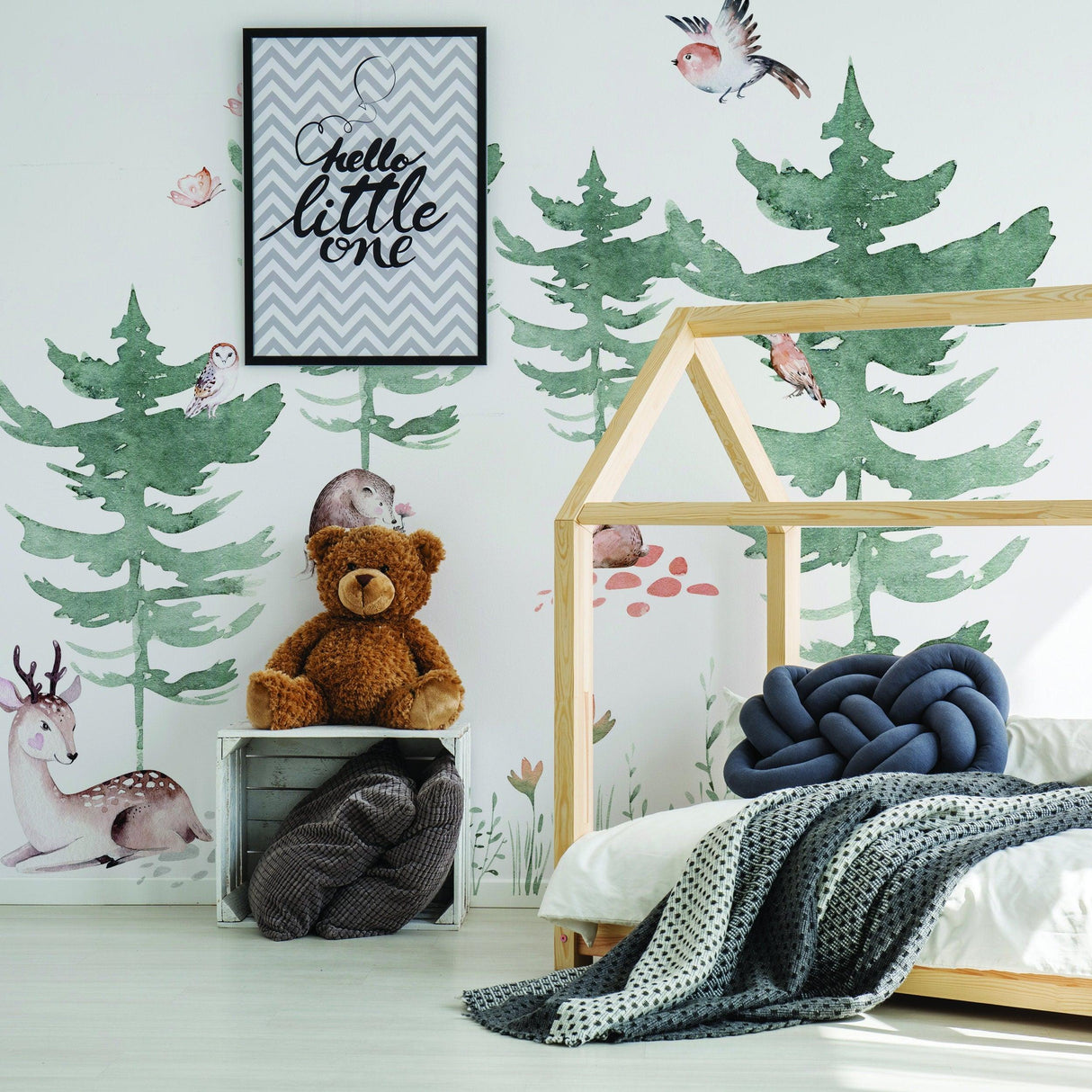 Forest animals wall decal in a kids room with green trees, a deer, and a teddy bear decor.