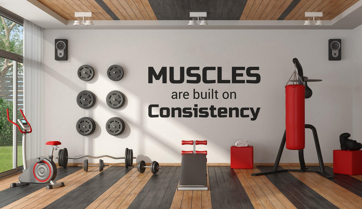 Motivational gym wall featuring the quote 'Muscles are built on Consistency' to inspire fitness goals.