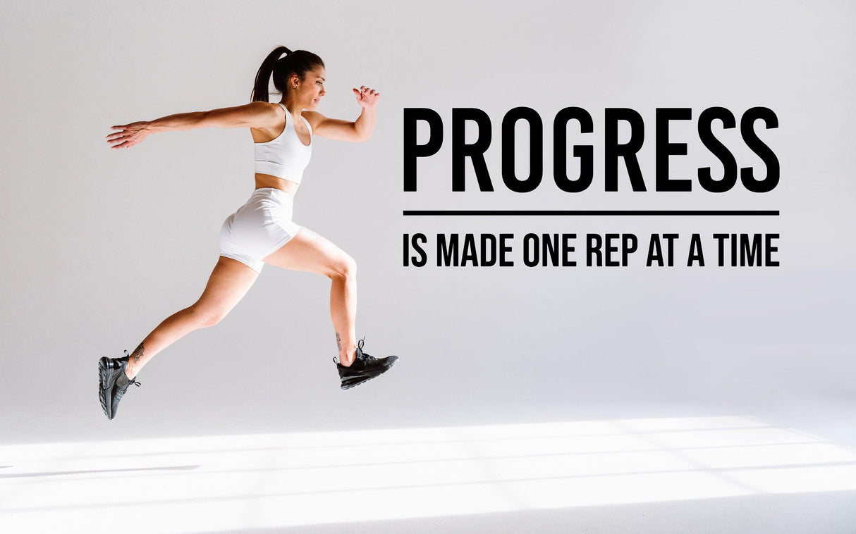 Motivational gym wall decal featuring the quote 'Progress is made one rep at a time' with an active woman jumping.