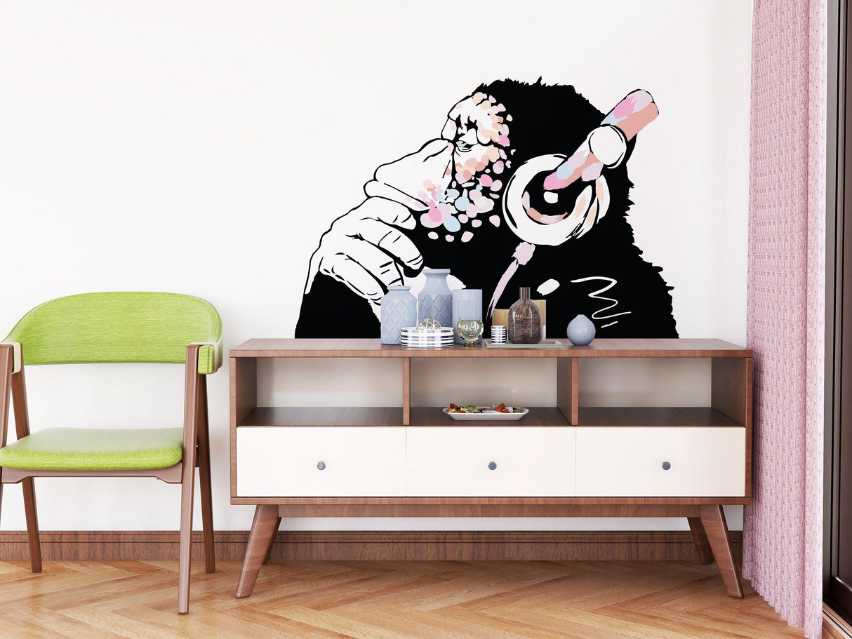Banksy-inspired pink thinking monkey vinyl decal on a wall above a modern sideboard in a boho-style room.