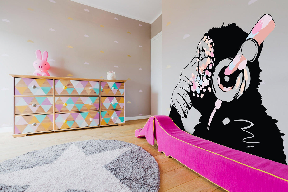 Banksy-inspired pink thinking monkey decal on wall, stylish boho girls room with colorful furniture.