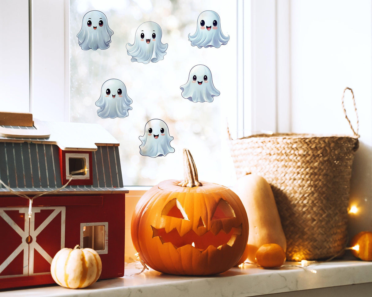 Frosted ghost window stickers on a window, Halloween decorations with a pumpkin and toy barn.