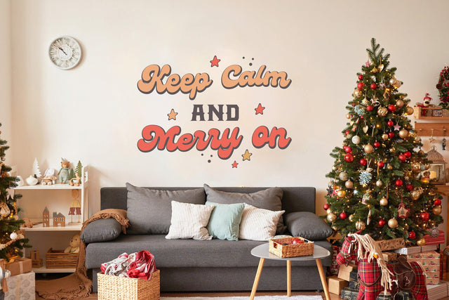 Whimsical Christmas wall decal saying 'Keep Calm and Merry On' above a cozy sofa and decorated Christmas trees.
