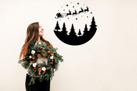 Woman holding a festive wreath with a Circular Santa Sleigh and Deers wall decal above, spreading Christmas cheer.