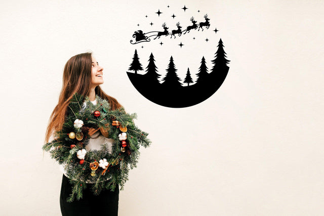 Woman holding a festive wreath with a Circular Santa Sleigh and Deers wall decal above, spreading Christmas cheer.