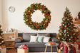 Christmas wreath wall decal above a cozy sofa, surrounded by decorated trees and holiday decor.