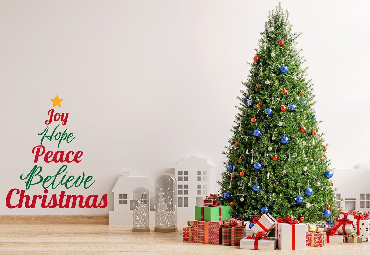 Christmas quote wall decal with "Joy Hope Peace Believe Christmas" next to a decorated tree and holiday gifts.