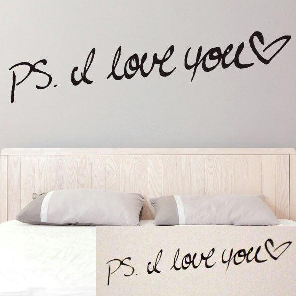 Custom personalized handwriting wall decal 'PS. I love you' above a bed.