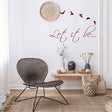 Motivational wall sticker "Let it be" with flying birds in a cozy interior setting.