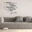 Motivational vinyl decal with quote by Socrates on an interior wall above a modern gray sofa.