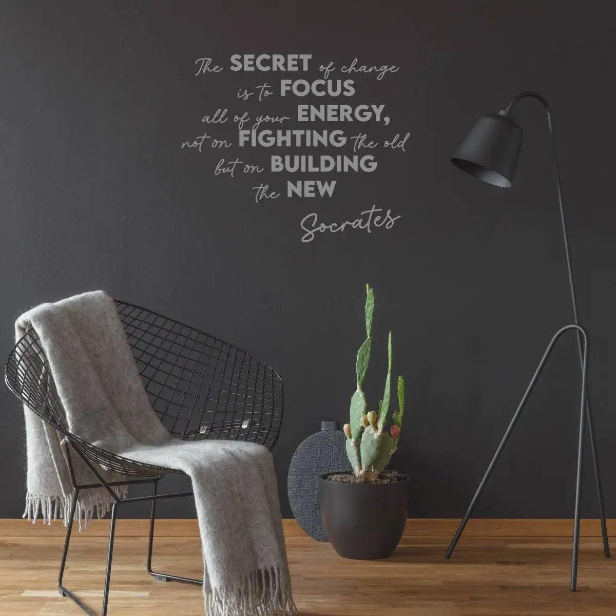 Motivational vinyl decal on dark wall featuring quote by Socrates, surrounded by modern decor and plant.