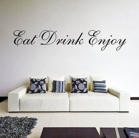 Eat Drink Enjoy vinyl wall decal above a white couch with patterned pillows in a stylish kitchen setting.