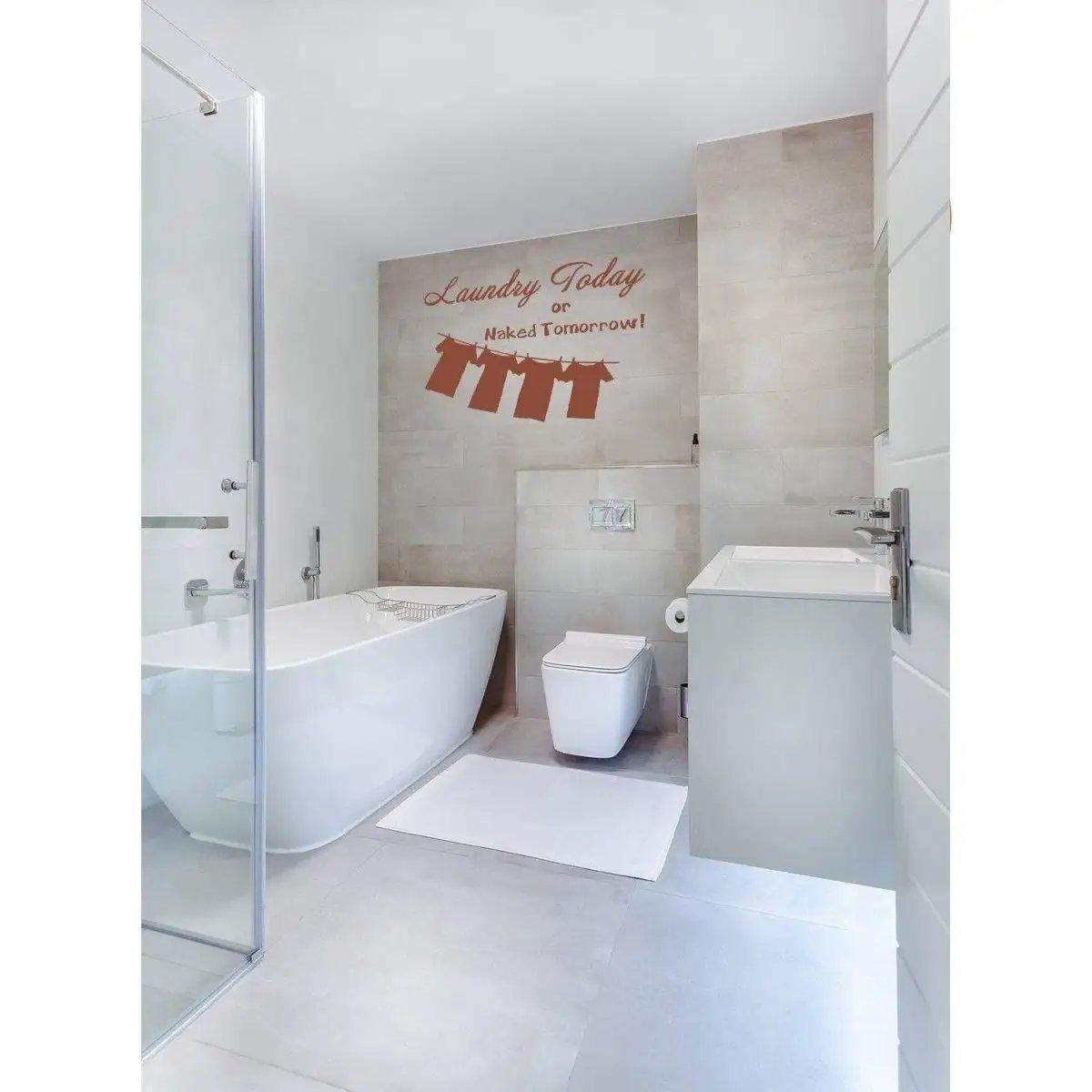 Elegant laundry room vinyl sticker saying 'Laundry Today or Naked Tomorrow!' above a stylish bathtub.