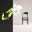 Glowing Guardian Angel wall sticker showcasing a luminescent angel figure beside a green chair in a modern room.
