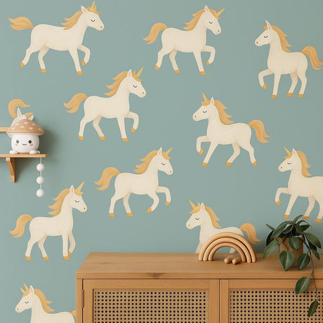A nursery wall featuring twelve pastel unicorn decals with golden manes and horns arranged over a teal background, above a wooden dresser with boho-style decor.