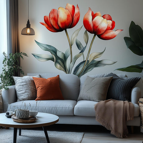 Two large red watercolor tulips with green leaves displayed as a wall decal above a modern light gray couch in a cozy living room setting.