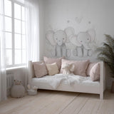 A soft-toned nursery with two hand-drawn baby elephant decals on the wall above a daybed, styled with blush pink pillows, a plush elephant toy, and natural wood accents in a serene, light-filled space.