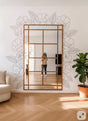 Vinyl wall decals of outline flowers and leaves arranged around a large rectangular mirror in a modern living room. The design is monochrome, cut from matte vinyl, and applied directly to the wall with no background.