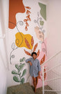 Large abstract botanical wall decal with colorful shapes and flowing lines applied to a staircase wall. The design includes orange and green leaves, organic lines, and large pink, yellow, and green color blocks on a white background.