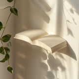 3D printed wall shelf shaped like an open book, mounted on a wall with soft natural light, minimalist modern home decor accessory