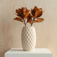 Cream-colored 3D printed vase with a diamond-patterned geometric texture, shown with brown dried leaves for illustration; flowers are not included.