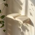 3D printed wall shelf shaped like an open book, mounted on a wall with soft natural light, minimalist modern home decor accessory