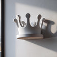 3D printed white crown-shaped wall shelf made from matte PLA, used as a small floating ledge on a light wall near a window.