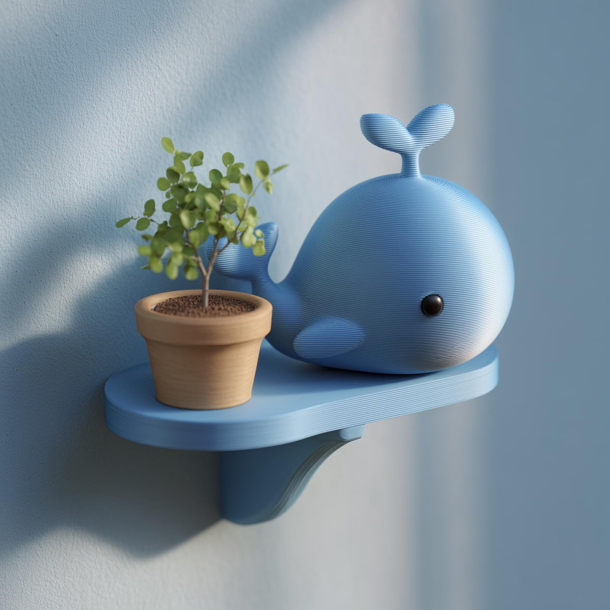 3D printed blue whale wall shelf with a small floating ledge, styled with a tiny plant pot, mounted on a light blue wall in soft natural light.