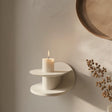 3D printed modern wall shelf in matte cream color, featuring a sculptural circular design with a candle displayed on top, minimalist home decor