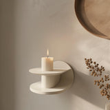 3D printed modern wall shelf in matte cream color, featuring a sculptural circular design with a candle displayed on top, minimalist home decor