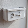 3D printed white wall-mounted organizer bin with an embossed wrench icon on the front, attached to a textured wall in a garage or utility room.