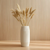 White 3D printed ribbed vase with vertical texture, holding dried grasses, displayed on a wooden surface in a minimalist modern setting