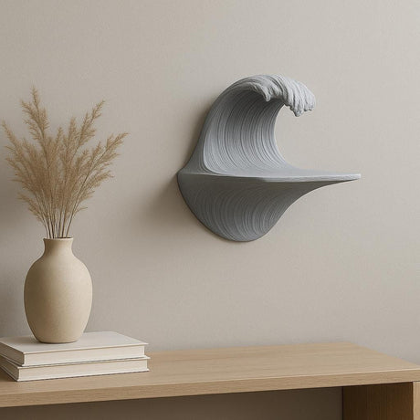 Sculptural grey 3D printed wall shelf shaped like a cresting wave, mounted on a beige wall above a wood cabinet with minimalist decor.