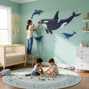 Realistic illustration of a large black and white orca swimming with two grey dolphins and two blue whales.