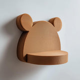 3D printed cute bear-shaped wall shelf with rounded ears and a small circular floating ledge, mounted on a clean minimalist wall.