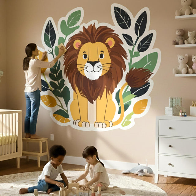 A cute, smiling cartoon lion with a brown mane sitting in front of a decorative wreath of dark green, light green, and orange leaves.