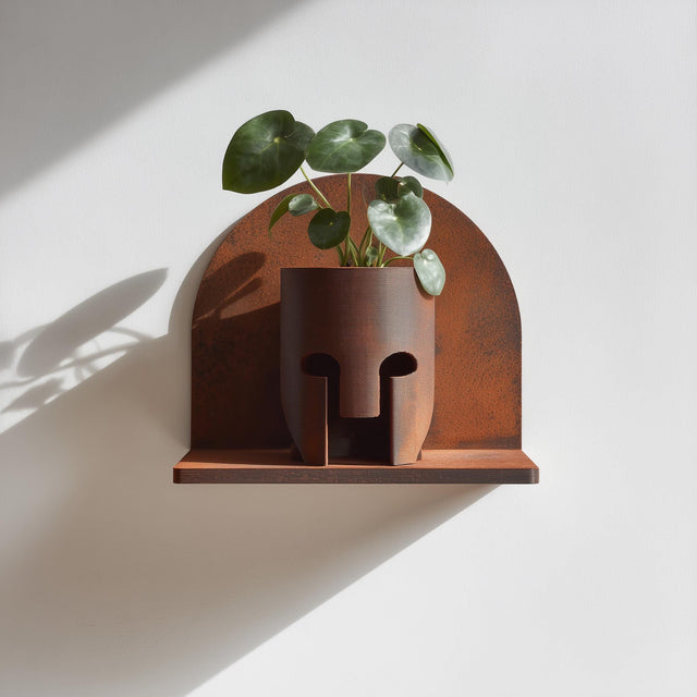 Wall-mounted 3D printed sculptural planter featuring an abstract face design with a small integrated ledge holding a plant.