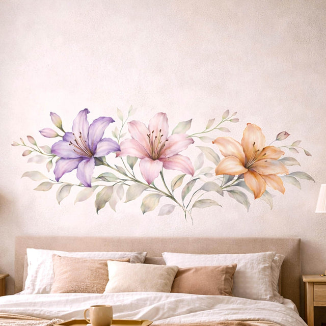 A horizontal watercolor illustration of three lilies in a row on a white background. From left to right: a light purple lily, a soft pink lily, and a warm peach lily. The flowers are connected by a central horizontal stem with delicate, pale green and grey leaves.