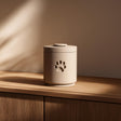 3D printed cylindrical pet cremation urn with a minimalist paw print detail, displayed as a modern memorial decor piece.