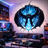 A 3D wall decal illustration of a black dragon breathing blue fire. The dragon has large wings spread wide and glowing blue eyes, appearing to burst through a circular hole in a white wall with realistic cracks radiating outward.